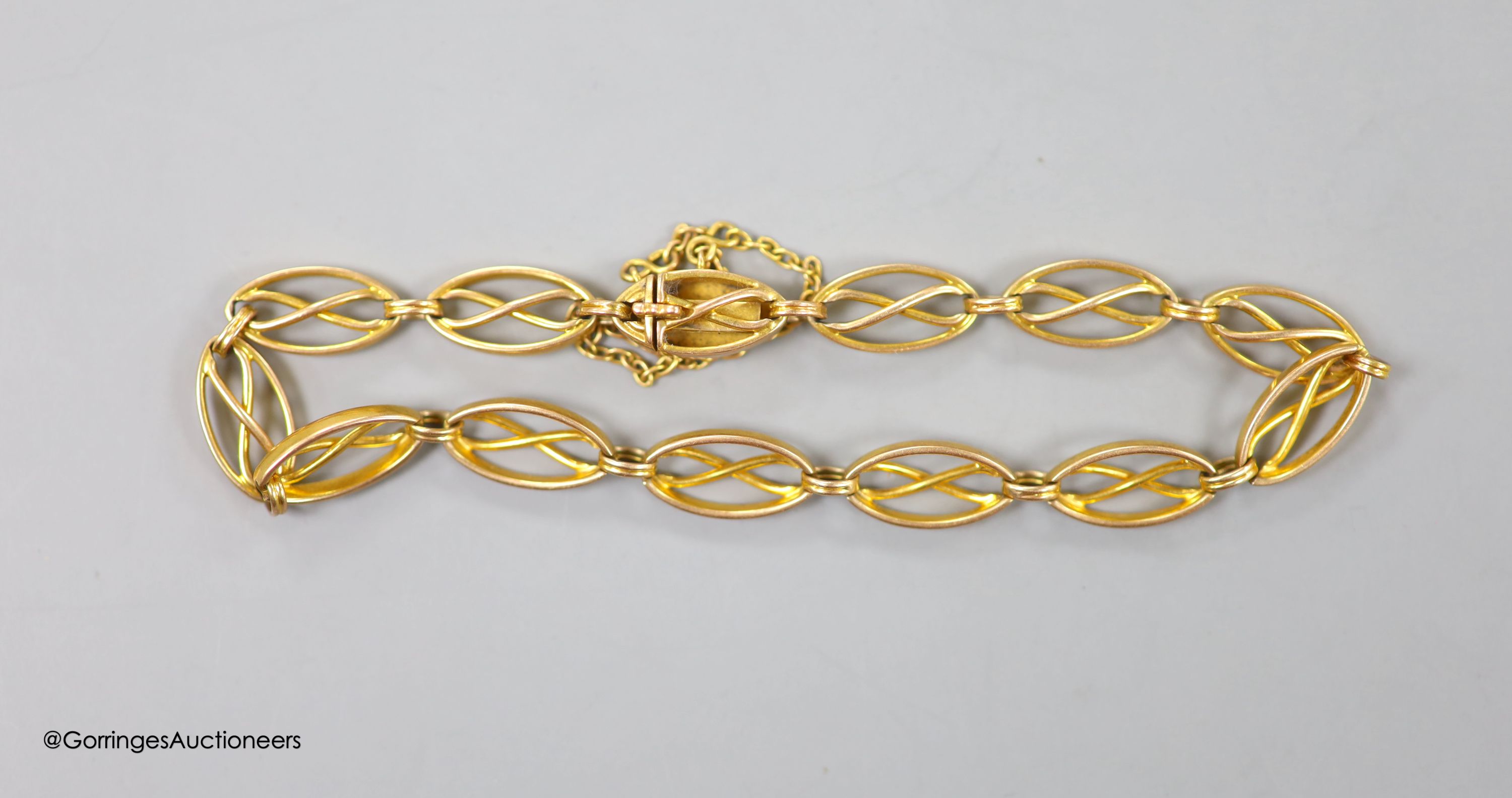 An Edwardian yellow metal (stamped 15) pierced oval link bracelet, with safety chain, approx. 17cm, 9.6 grams.